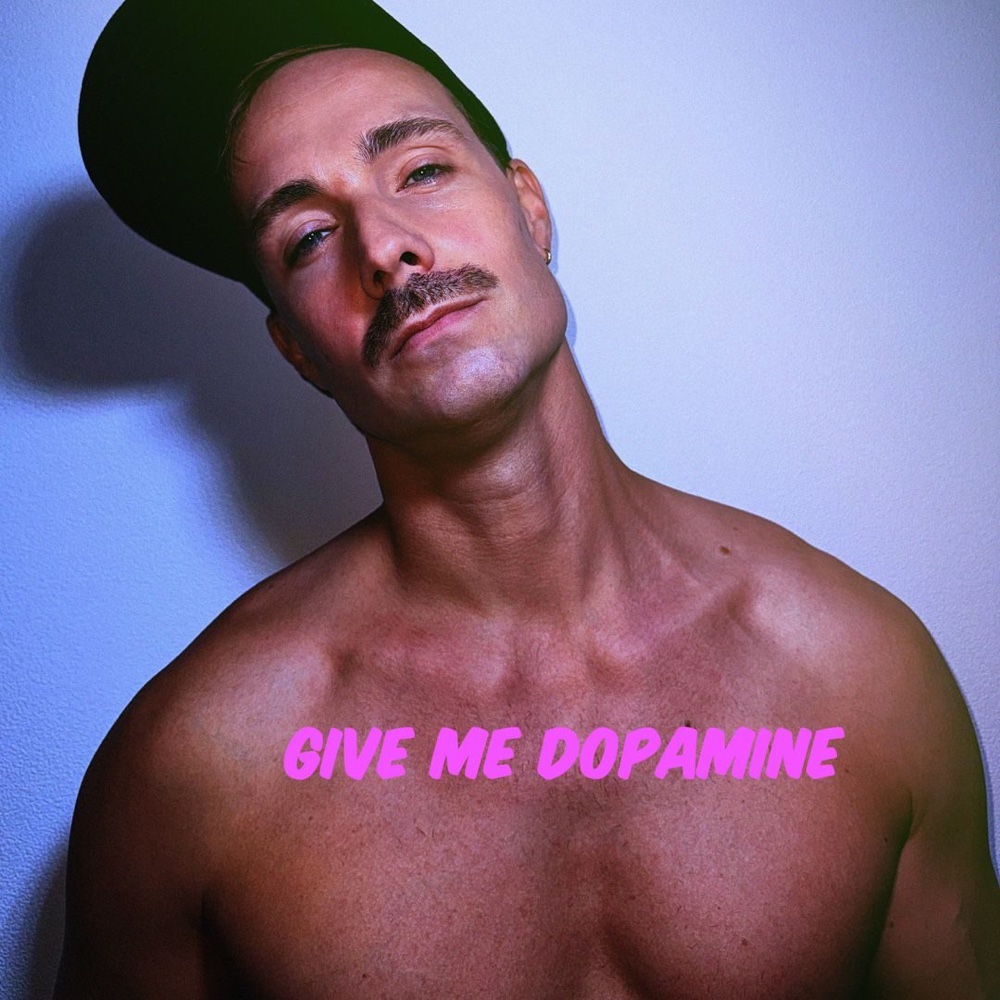 Give Me Dopamine single artwork: Milo in a black cap against a blue wall, with the title in neon pink.